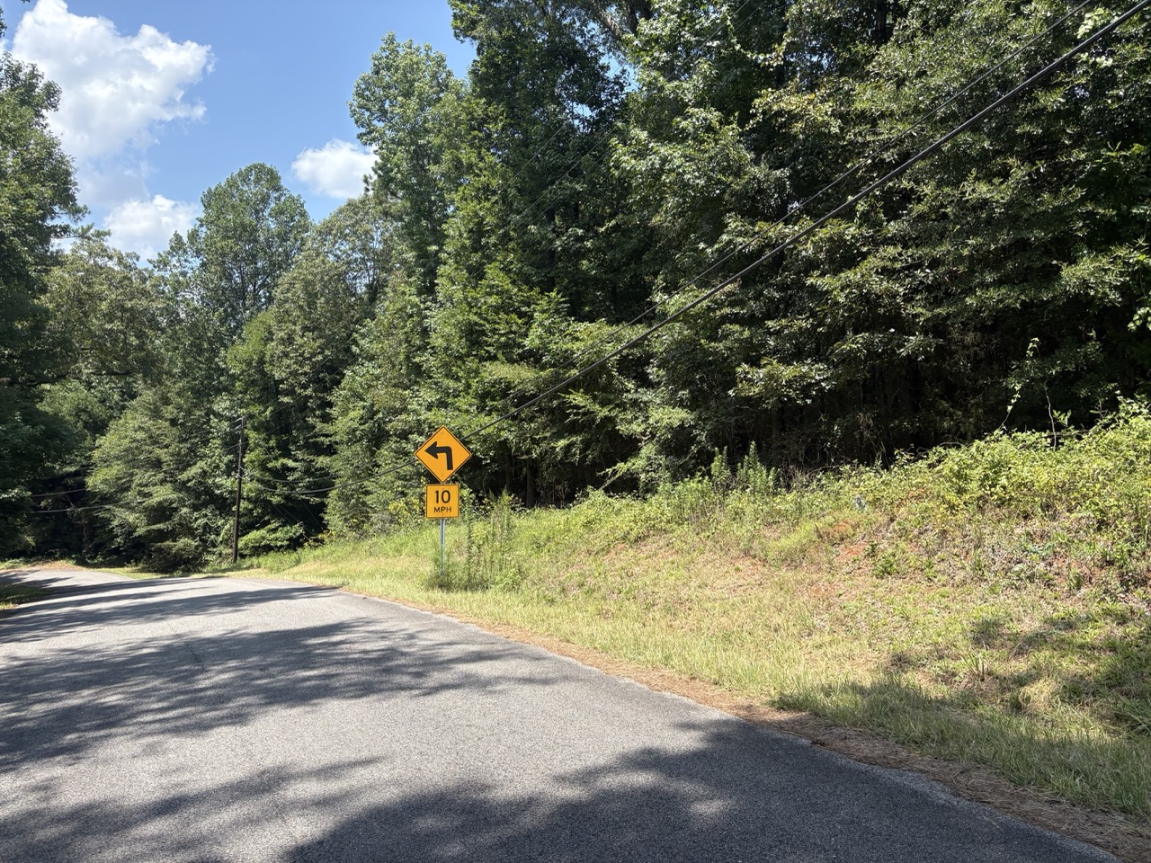 Street-level frontage and a sloping grassy bank at a Woodmont Subdivision lot