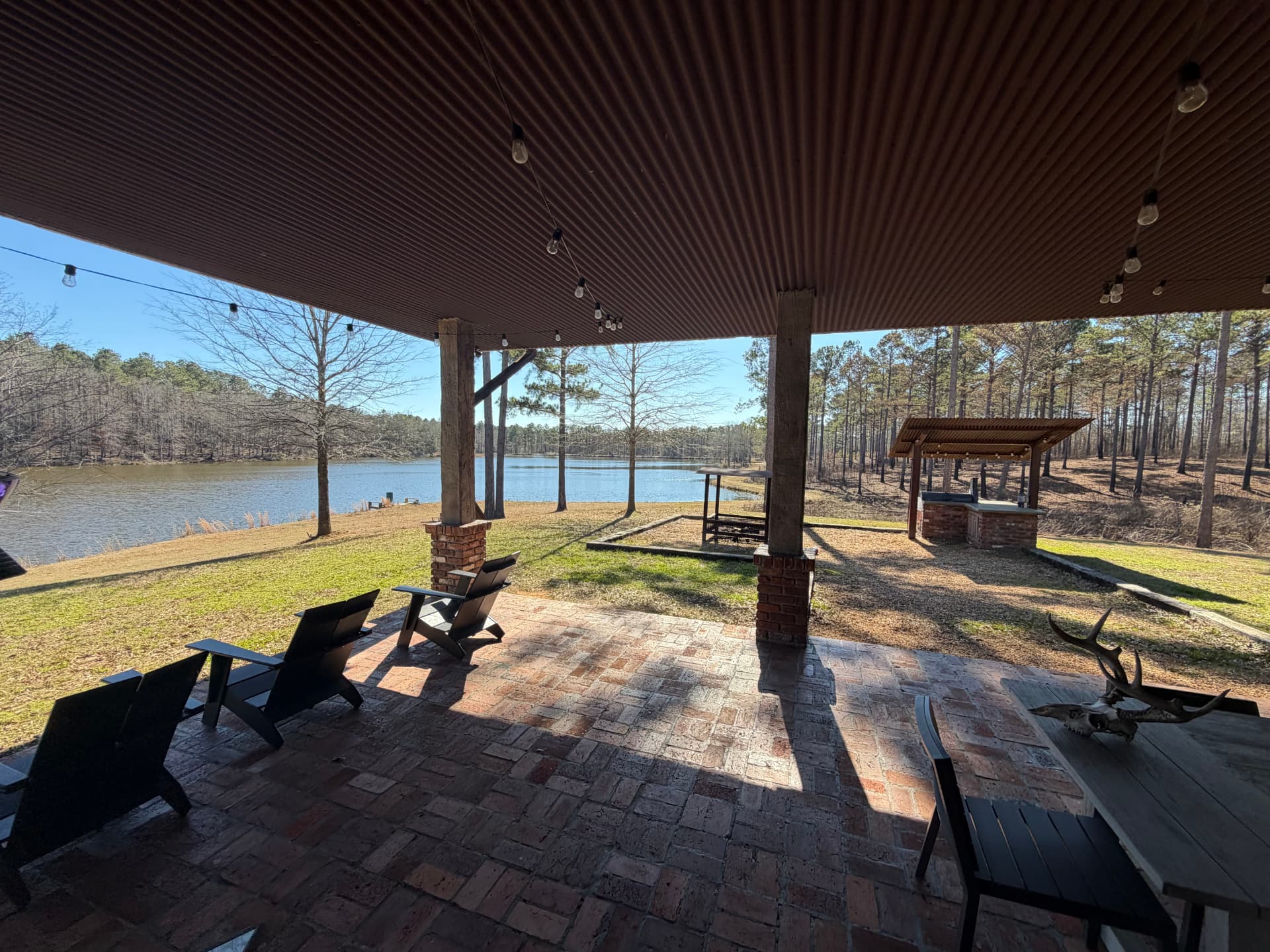 Covered patio with chairs overlooking a lake surrounded by pines