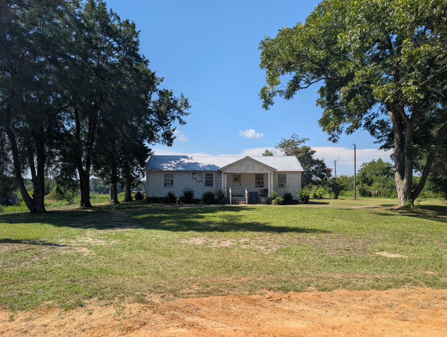 The front of the residence across a grassy yard bordered by large trees