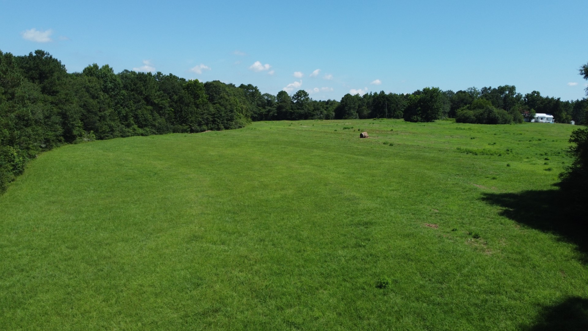 Aerial of the pasture with a round bale and the house in the distance