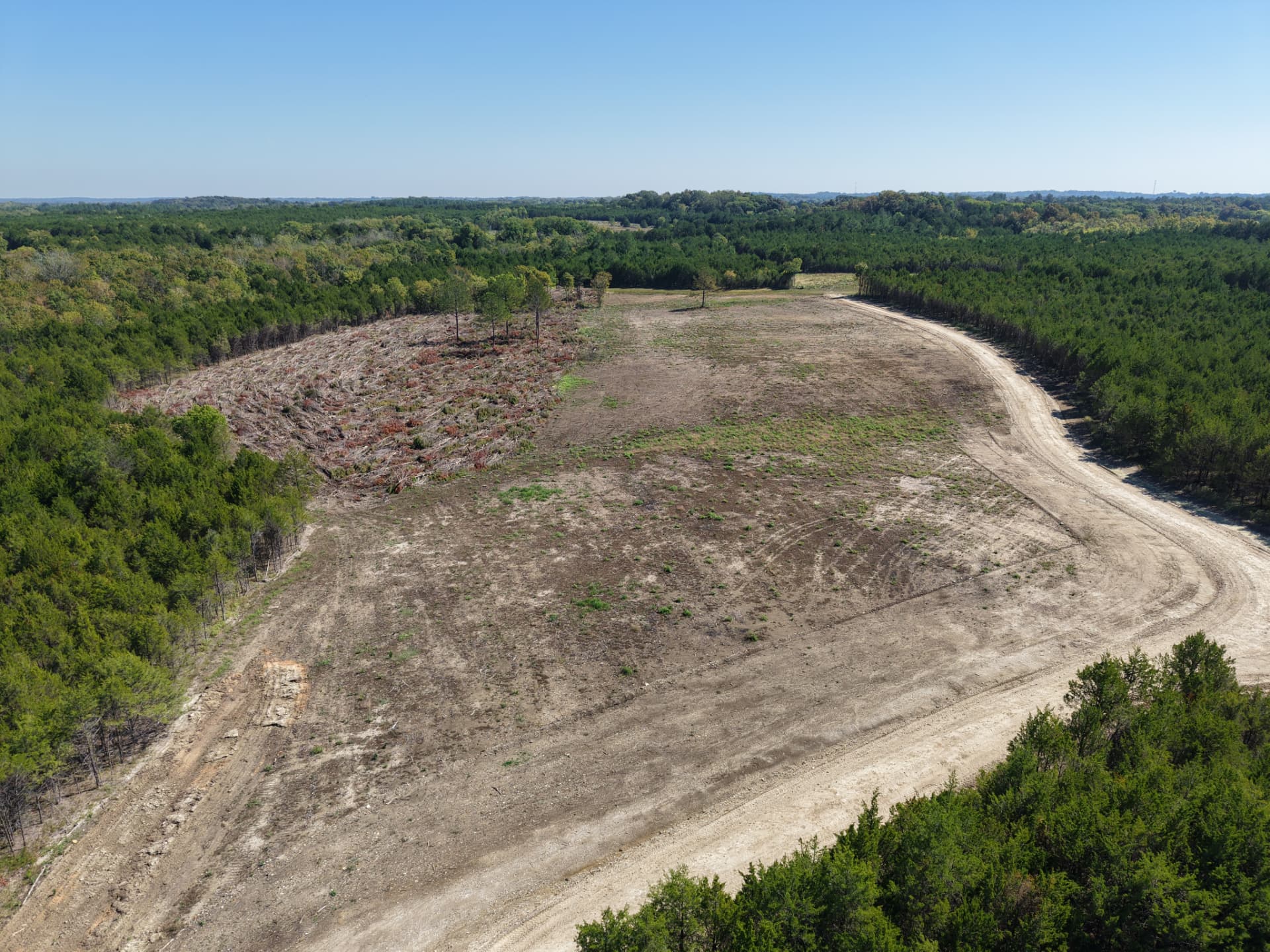 Aerial of a broad cleared area suitable for a potential homesite or food plot, surrounded by timber