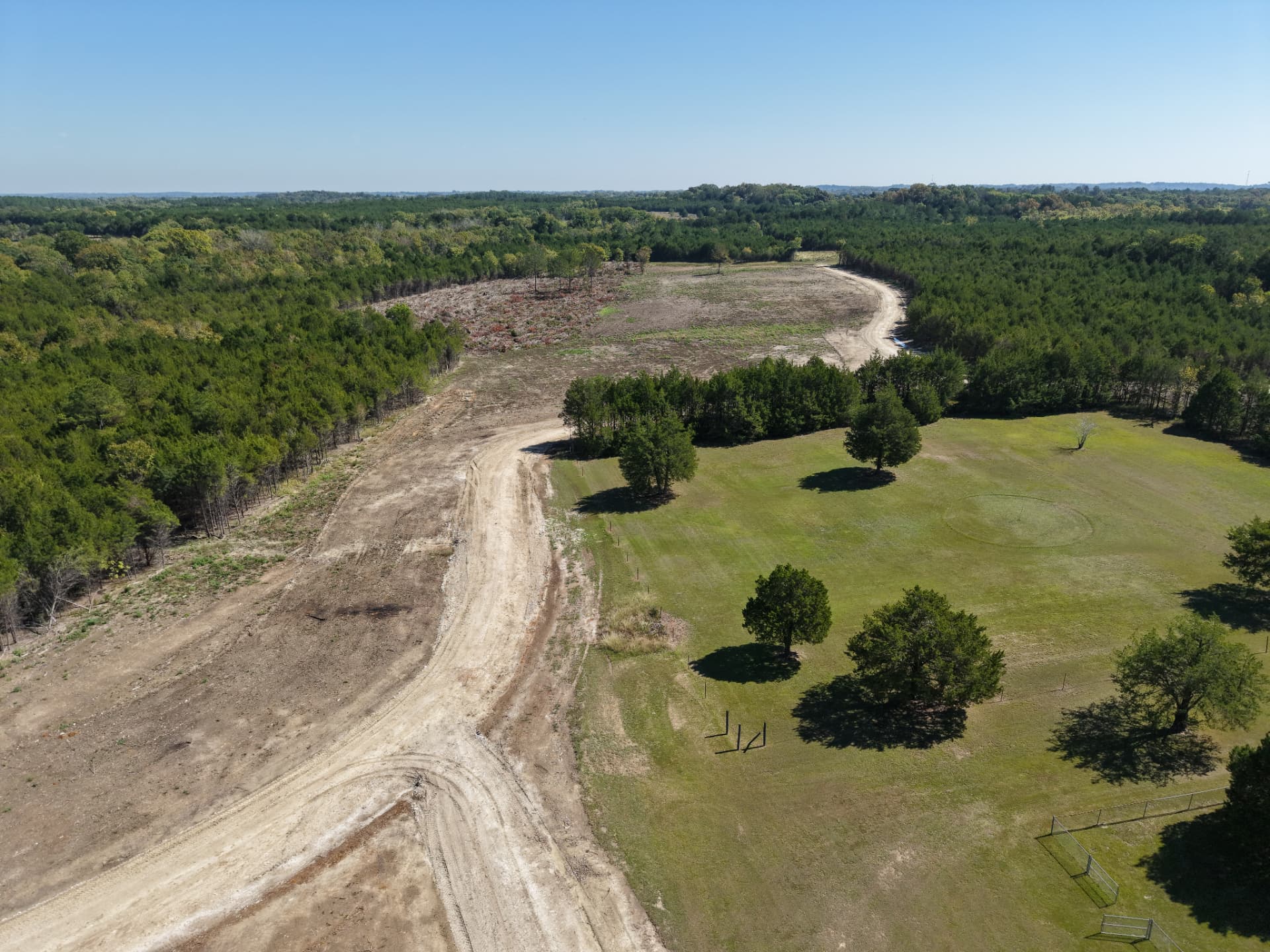 Aerial of the new private driveway curving toward a cleared homesite area at Cedar Junction