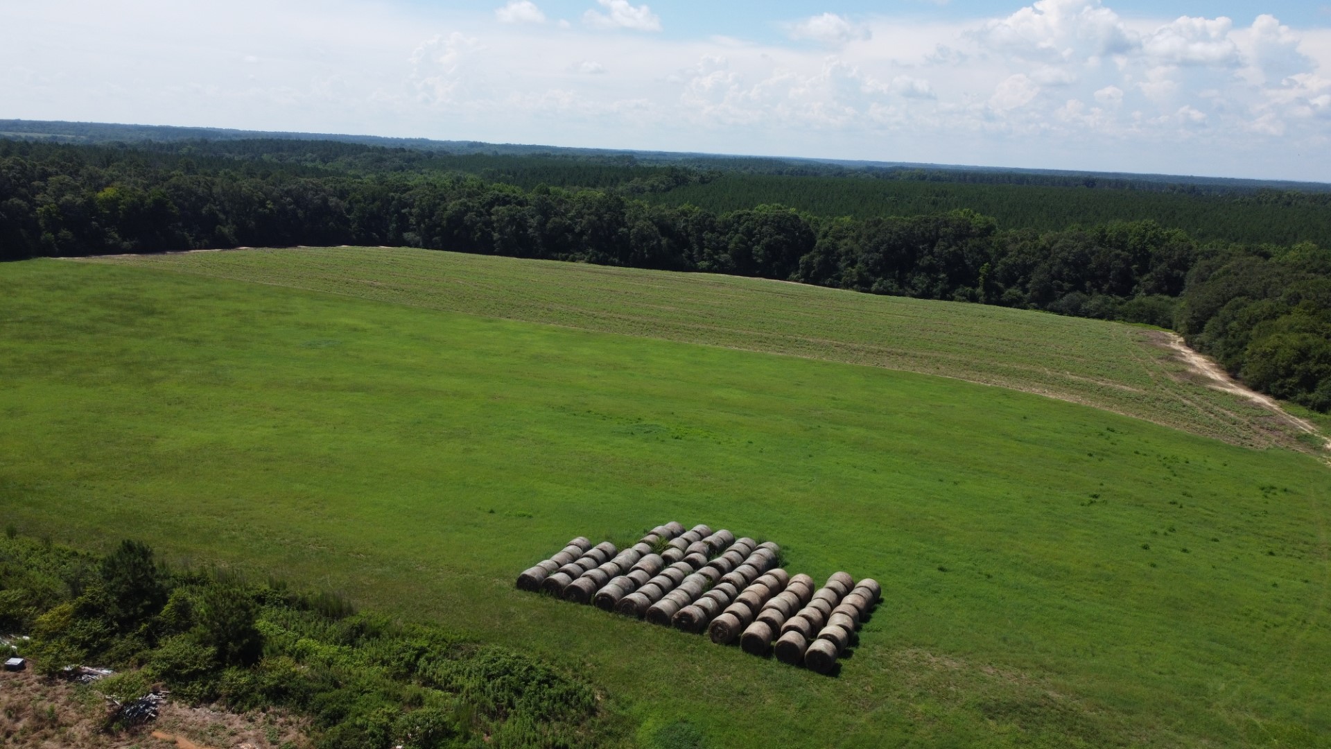 Aerial of the pasture with round bales and timber beyond